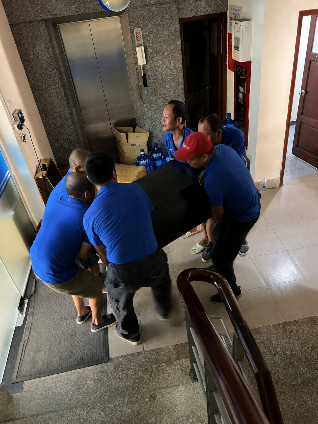Nhân viên vận chuyển két sắt bằng cầu thang tại nhà khách hàng