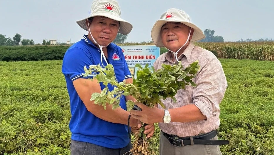 TS. Nguyễn Thanh Phương (bên phải) chụp ảnh cùng nông dân tham gia mô hình ruộng đậu phộng sử dụng phân bón công nghệ mới. Ảnh: Mỹ Hạnh